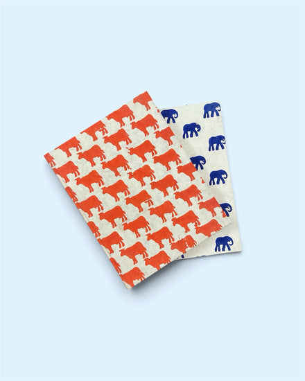 Bombay Paperie handcrafted notebooks with orange cow and blue elephant block-printed motifs on eco-friendly paper.